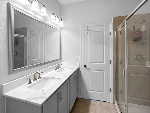 bathroom with dual vanity, a shower with door, and tile patterned flooring