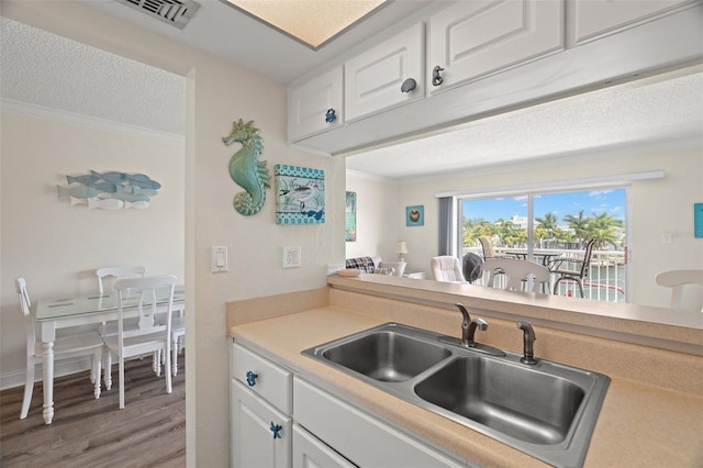 kitchen featuring ornamental molding, sink, hardwood / wood-style floors, and white cabinets