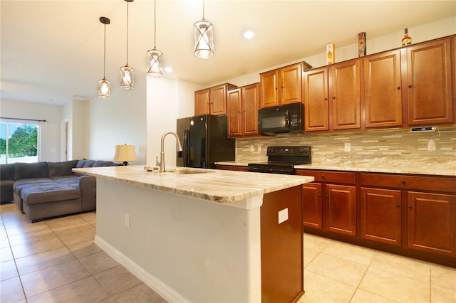 kitchen with backsplash, a kitchen island with sink, sink, black appliances, and decorative light fixtures