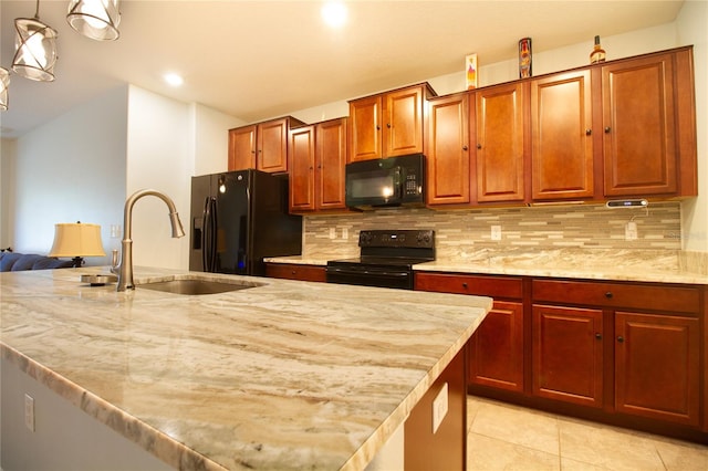 kitchen with pendant lighting, backsplash, a kitchen island with sink, black appliances, and sink