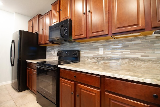 kitchen with light tile patterned floors, tasteful backsplash, light stone counters, and black appliances