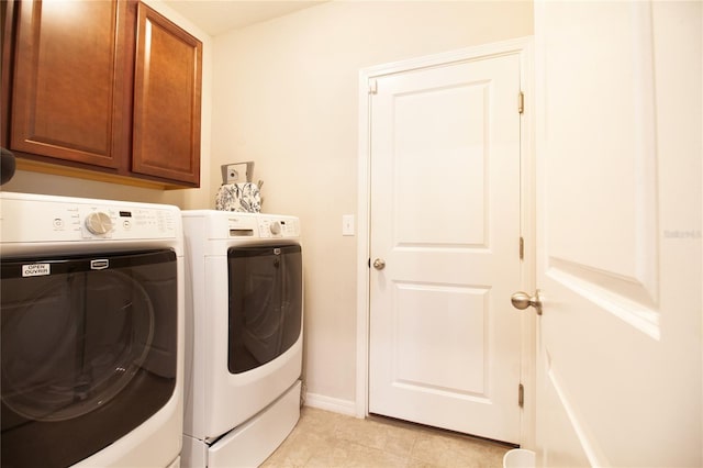 clothes washing area with cabinets, light tile patterned floors, and washing machine and clothes dryer