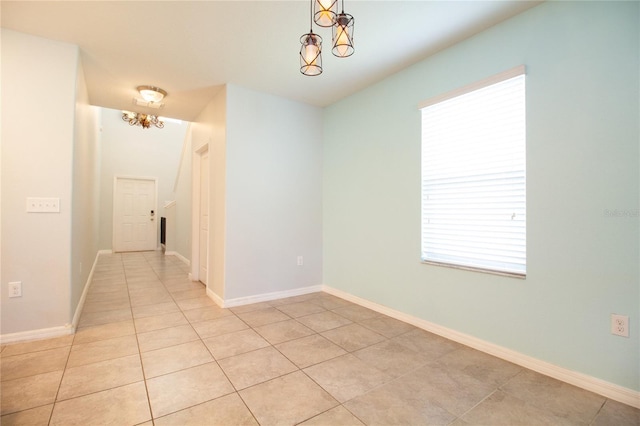 tiled spare room with a chandelier and plenty of natural light