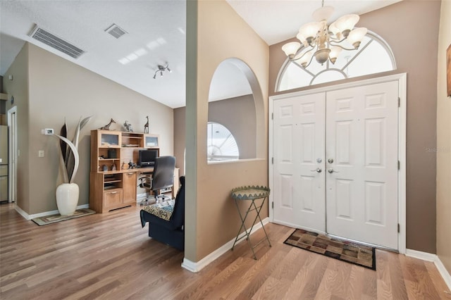 foyer with hardwood / wood-style floors and a notable chandelier