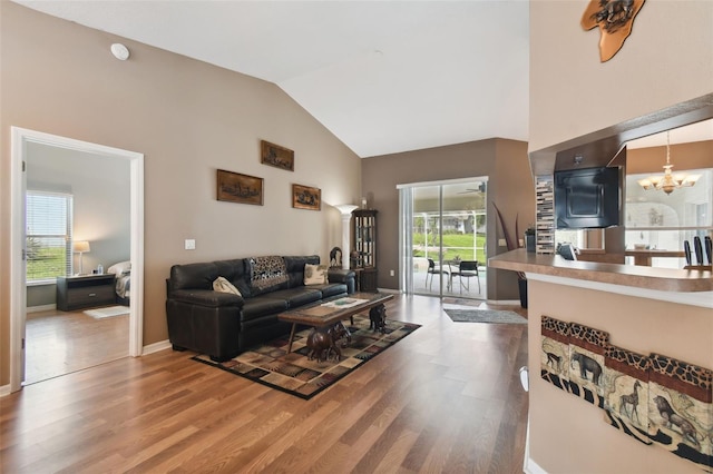 living room featuring hardwood / wood-style floors, high vaulted ceiling, and a chandelier