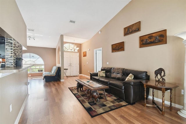 living room with wood-type flooring, high vaulted ceiling, a chandelier, and track lighting