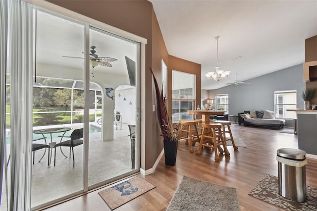 dining space with wood-type flooring, vaulted ceiling, and ceiling fan with notable chandelier