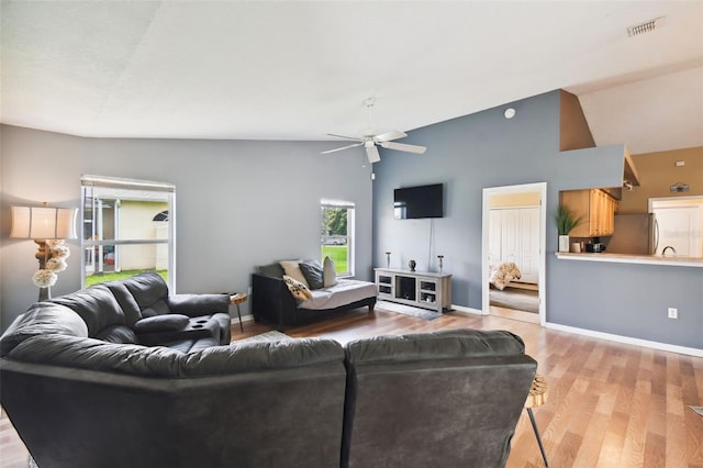 living room with ceiling fan, high vaulted ceiling, and light wood-type flooring