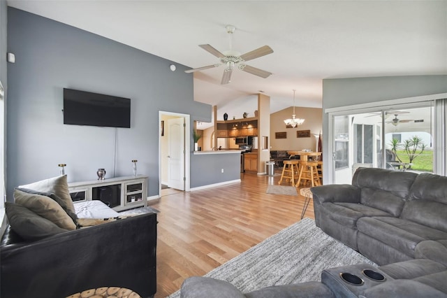 living room with hardwood / wood-style flooring, vaulted ceiling, and ceiling fan with notable chandelier