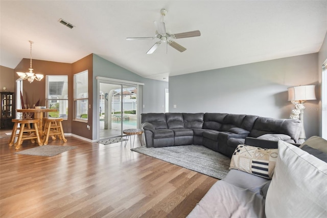 living room with ceiling fan with notable chandelier, lofted ceiling, and hardwood / wood-style floors