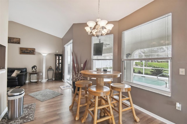 dining space featuring lofted ceiling, hardwood / wood-style floors, and an inviting chandelier