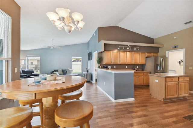 kitchen with wood-type flooring, vaulted ceiling, stainless steel fridge with ice dispenser, a kitchen island, and pendant lighting