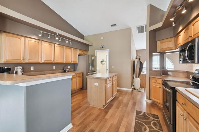 kitchen with vaulted ceiling, light brown cabinetry, a center island, stainless steel appliances, and light wood-type flooring