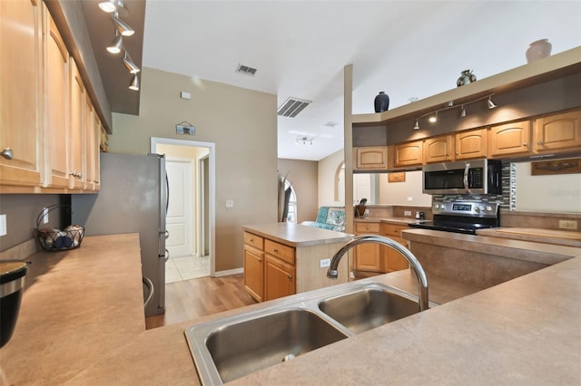 kitchen featuring track lighting, appliances with stainless steel finishes, sink, and light hardwood / wood-style flooring