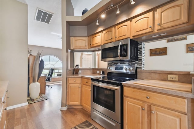 kitchen with stainless steel appliances, track lighting, backsplash, and light wood-type flooring