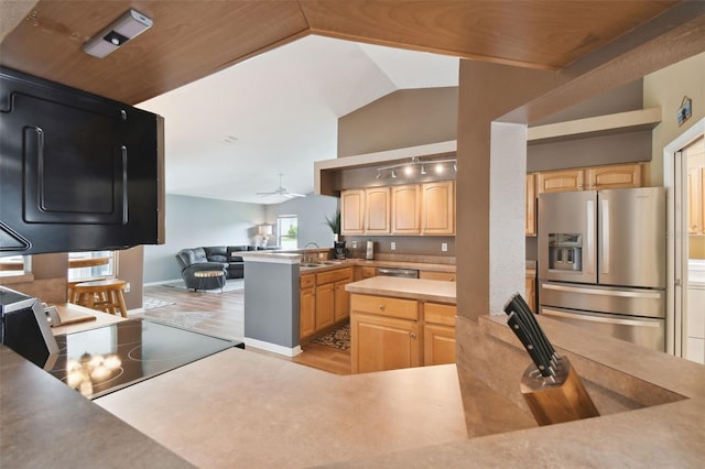 kitchen with stainless steel refrigerator with ice dispenser, vaulted ceiling, light brown cabinets, and kitchen peninsula