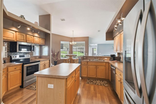 kitchen featuring a kitchen island, appliances with stainless steel finishes, sink, kitchen peninsula, and light hardwood / wood-style flooring