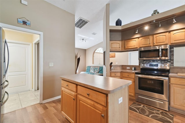 kitchen featuring rail lighting, light hardwood / wood-style floors, a center island, and appliances with stainless steel finishes