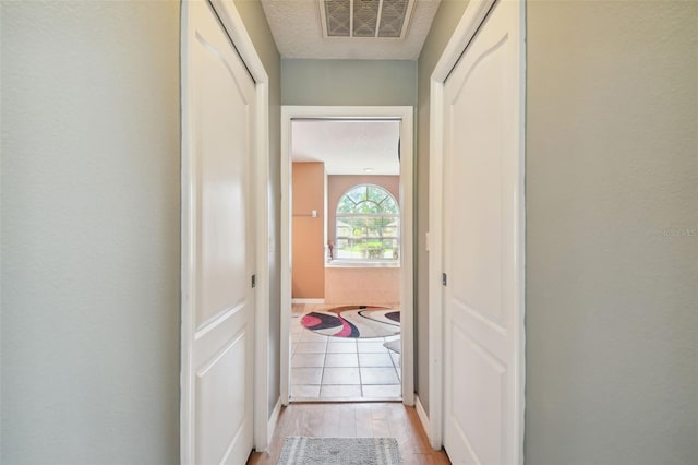 corridor with a textured ceiling and light wood-type flooring