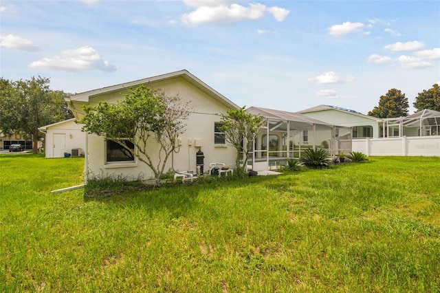 rear view of house with a lanai, central AC, and a lawn