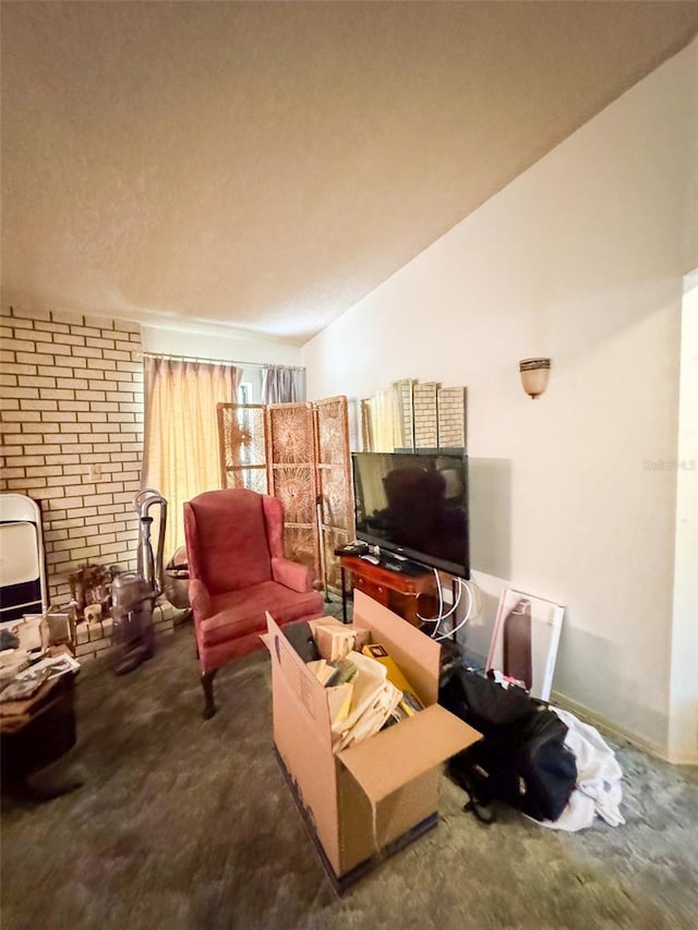 carpeted living room featuring brick wall