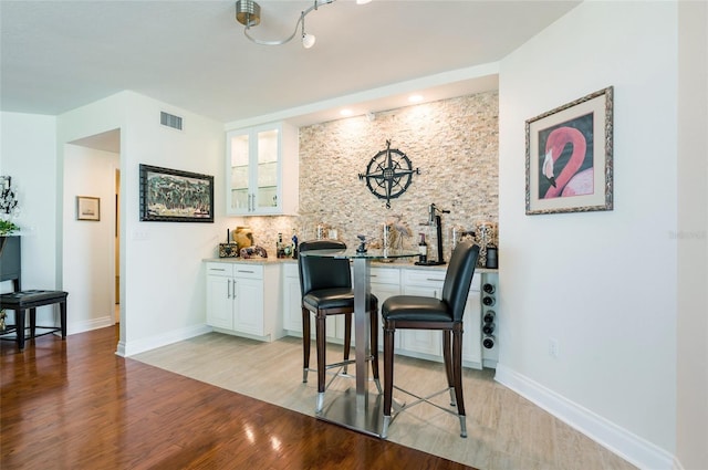 interior space featuring light hardwood / wood-style flooring, white cabinets, and track lighting