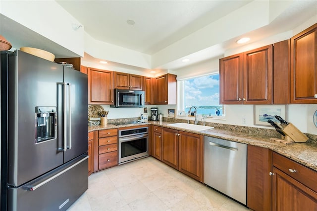 kitchen featuring light tile patterned flooring, sink, stainless steel appliances, and light stone counters