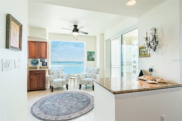 kitchen with ceiling fan, dark stone counters, and kitchen peninsula