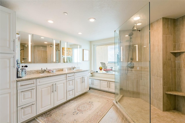 bathroom featuring an enclosed shower, double sink vanity, and tile patterned flooring