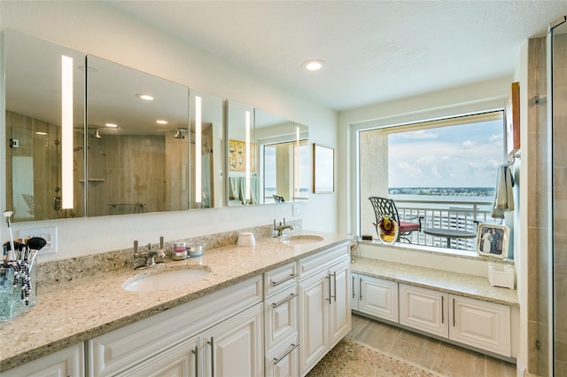 bathroom featuring dual bowl vanity, a water view, and an enclosed shower