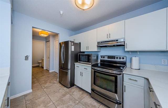kitchen with a textured ceiling, light stone countertops, white cabinets, and appliances with stainless steel finishes