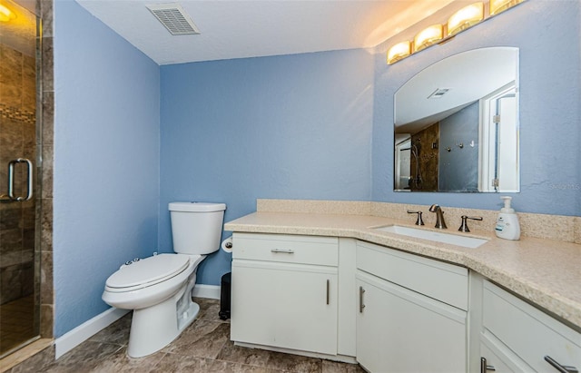 bathroom featuring vanity, a shower with shower door, and toilet