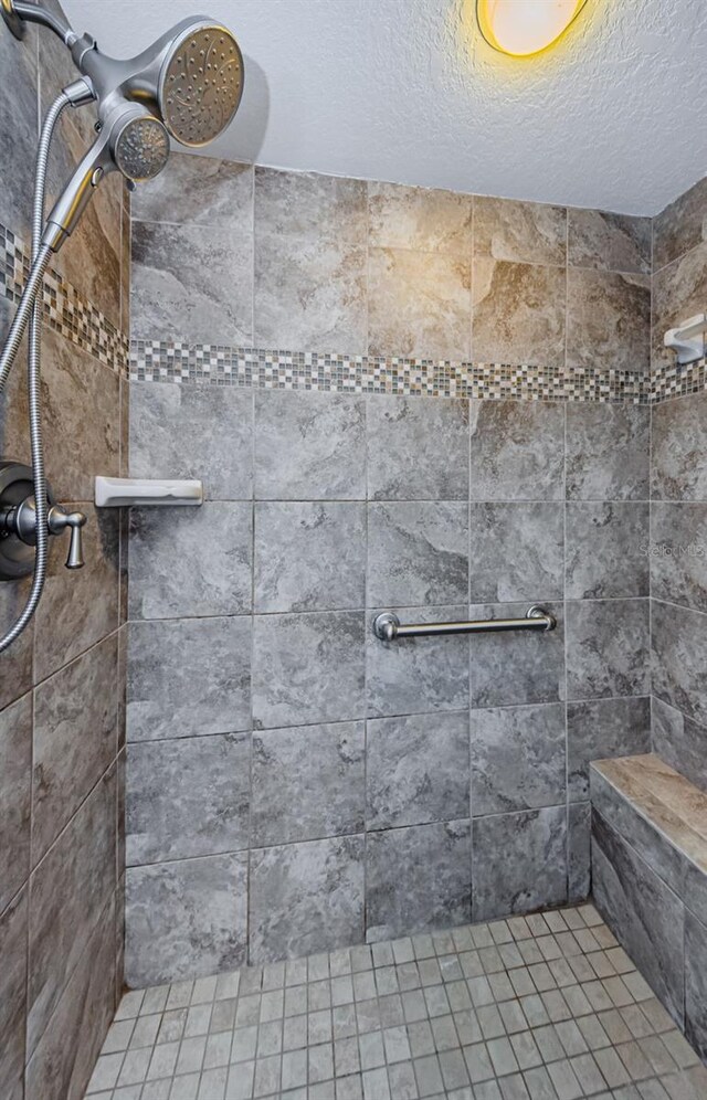 bathroom with a tile shower and a textured ceiling