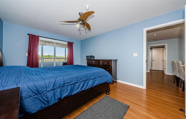 bedroom with hardwood / wood-style floors, a textured ceiling, access to outside, and ceiling fan
