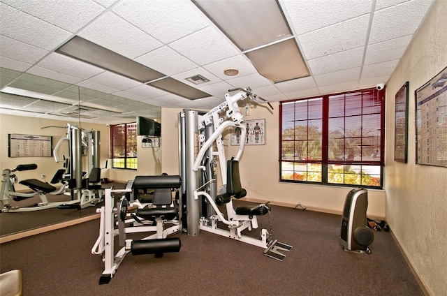 gym with a drop ceiling and a healthy amount of sunlight