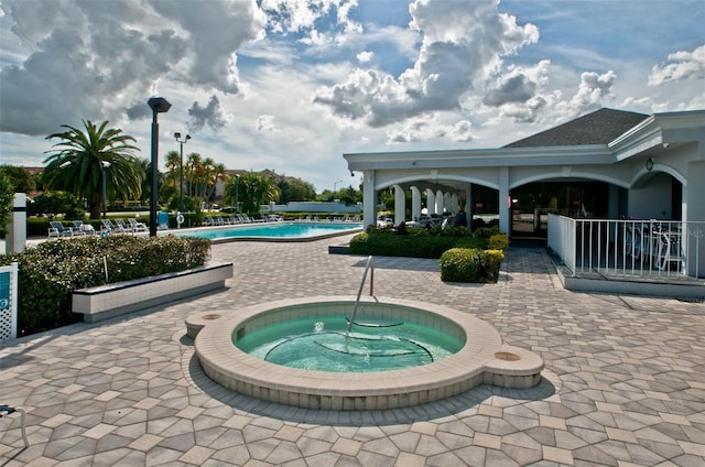 view of swimming pool featuring a hot tub and a patio area