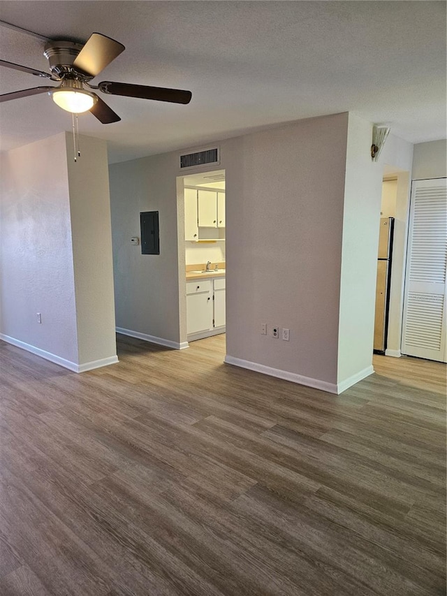 unfurnished living room featuring electric panel, hardwood / wood-style floors, and ceiling fan