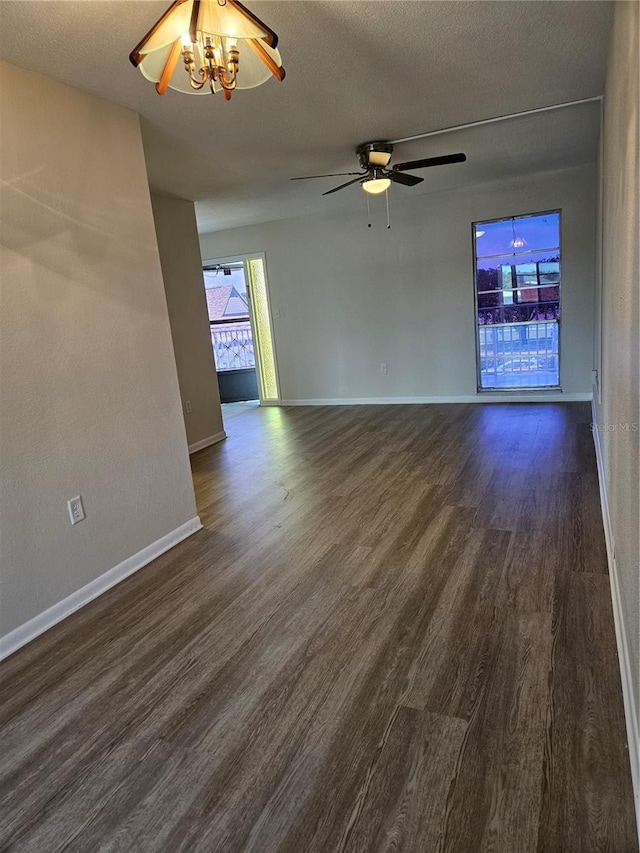 spare room with ceiling fan with notable chandelier, a textured ceiling, and dark hardwood / wood-style floors