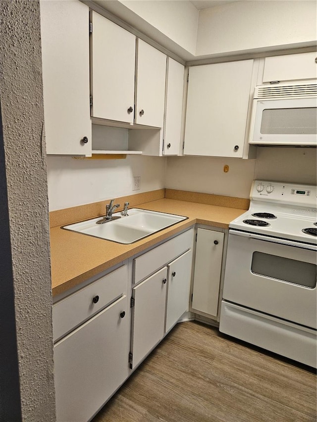 kitchen with white appliances, light hardwood / wood-style flooring, sink, and white cabinetry