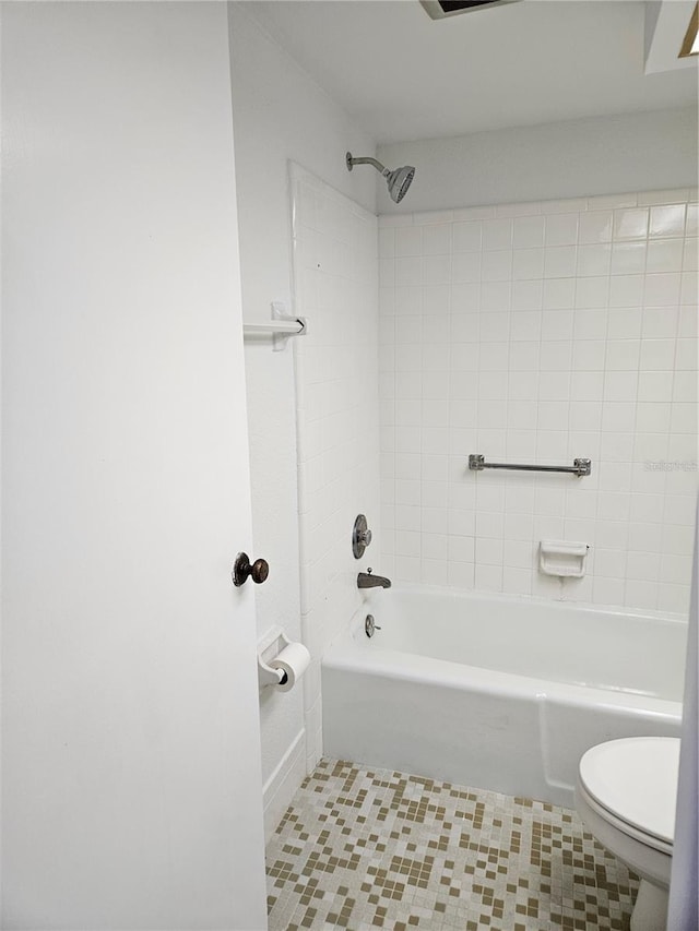 bathroom featuring toilet, tiled shower / bath combo, and tile patterned flooring