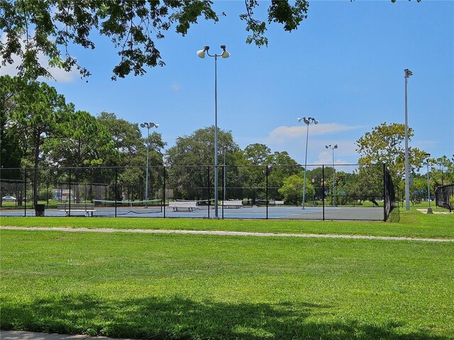 view of home's community featuring tennis court and a lawn