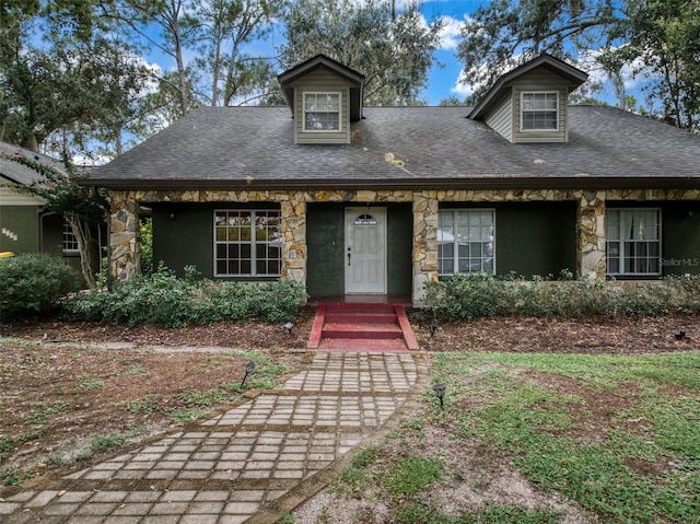 view of front of house featuring stone siding and roof with shingles