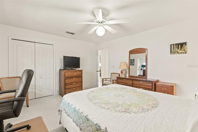 bedroom with ceiling fan, light carpet, and a closet