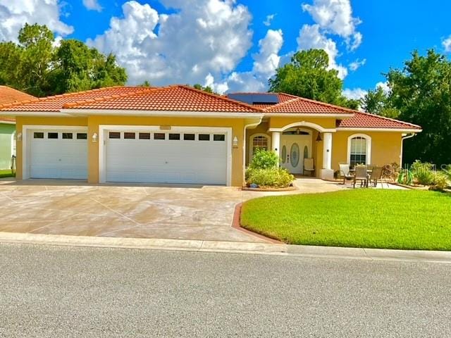 mediterranean / spanish-style house with solar panels, a front yard, and a garage