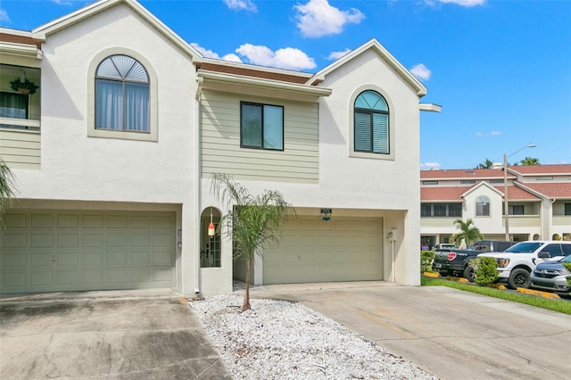 view of property with concrete driveway, an attached garage, and stucco siding