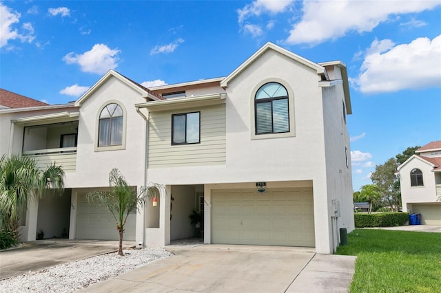 view of front of home with a garage, a front yard, concrete driveway, and stucco siding