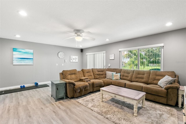 living area with a textured ceiling, recessed lighting, a ceiling fan, baseboards, and light wood finished floors