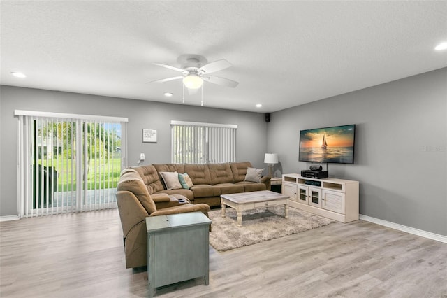 living area with light wood-type flooring, ceiling fan, baseboards, and a textured ceiling