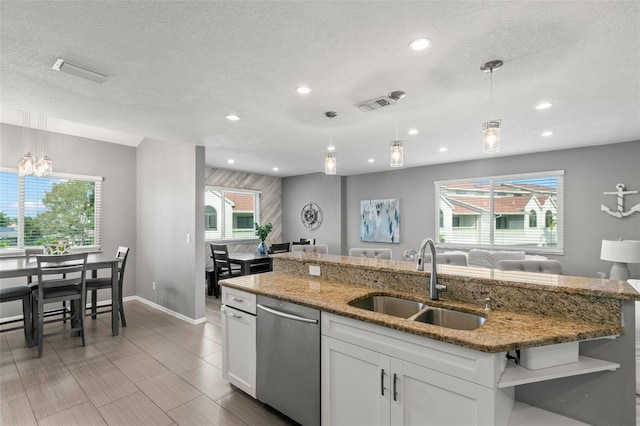 kitchen featuring pendant lighting, stainless steel dishwasher, a sink, and white cabinets