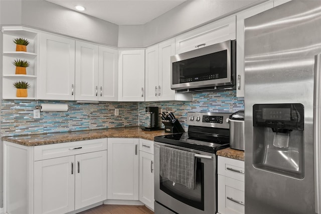 kitchen with dark stone counters, open shelves, appliances with stainless steel finishes, and white cabinets